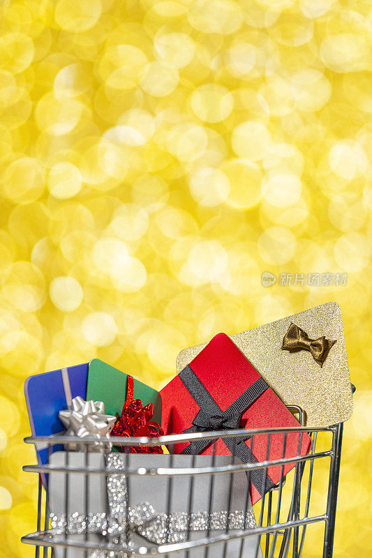 Close-up of a shopping cart full of wrapped gift cards against gold colored bokeh background – Concept online shopping